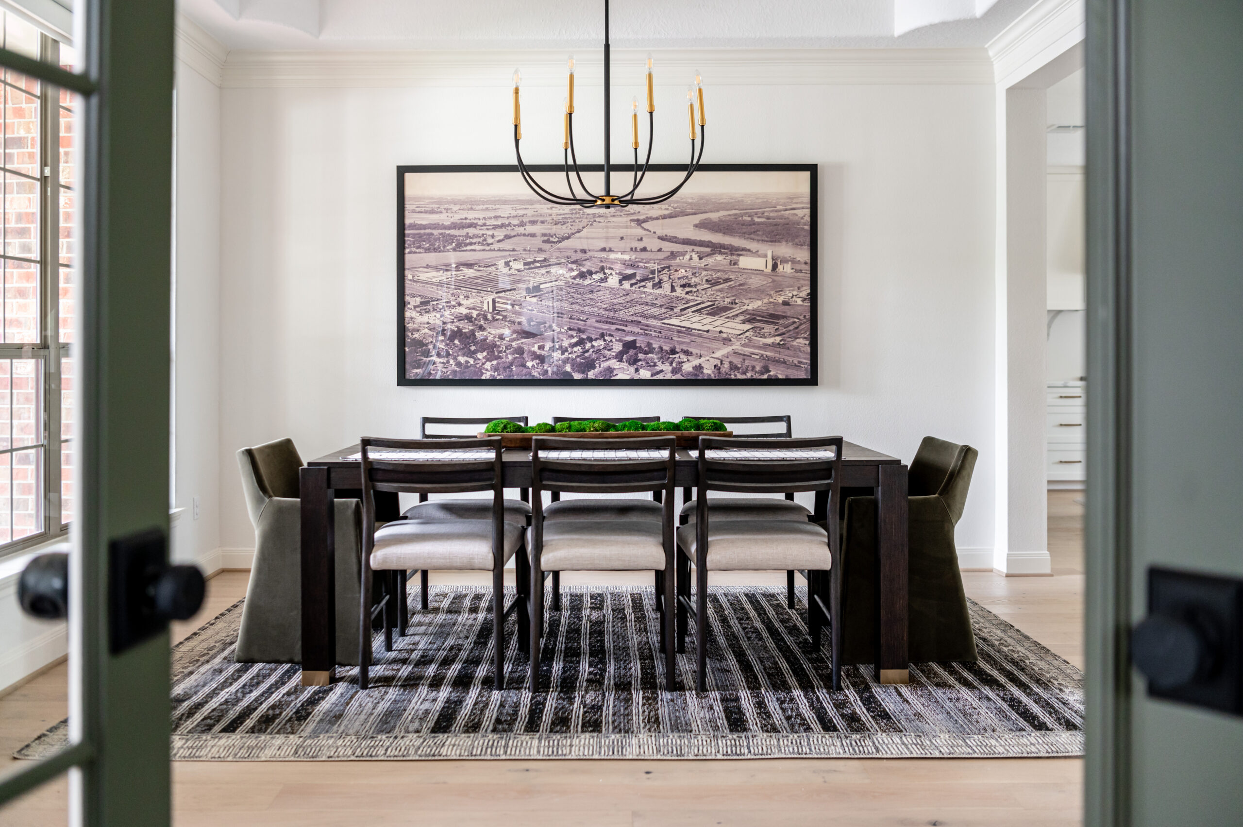  A dining space with a vintage-style photograph above the table, highlighted by modern lighting and minimalistic decor, featured in a modern design concept for interior design publications.