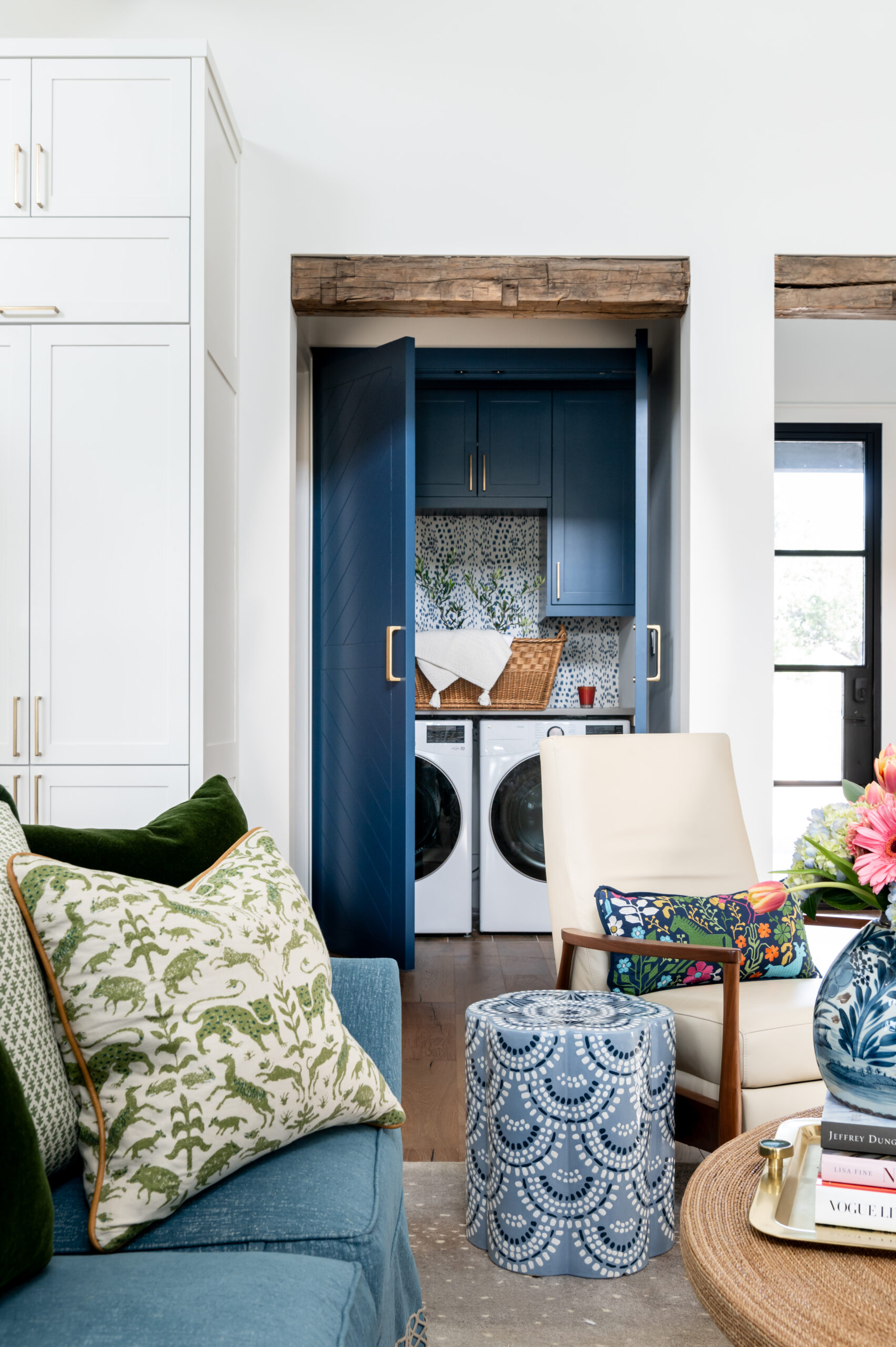 Laundry area featuring blue cabinetry with a patterned backsplash and shelves.
