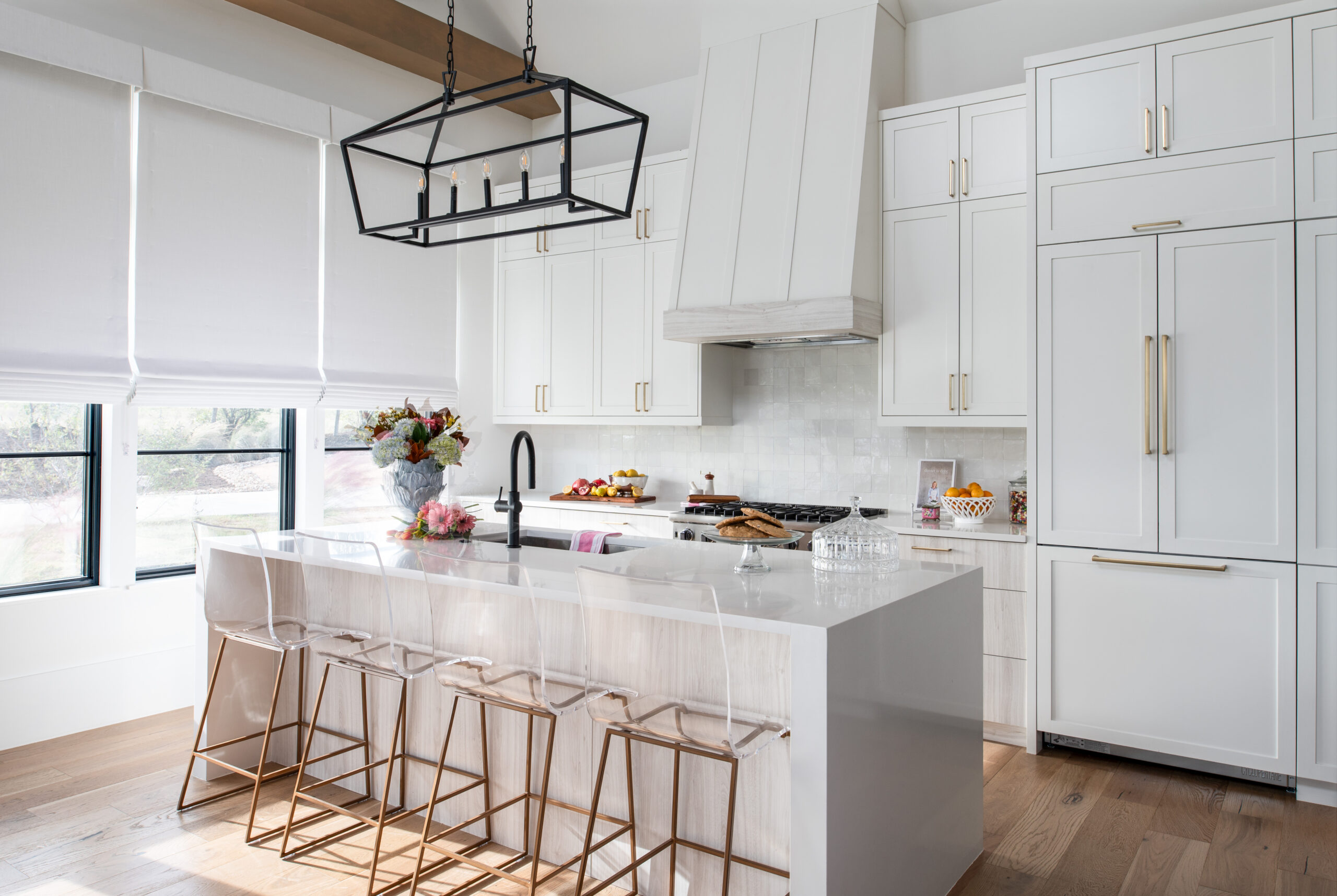 A large open kitchen with white cabinetry, an island, and modern lighting.
