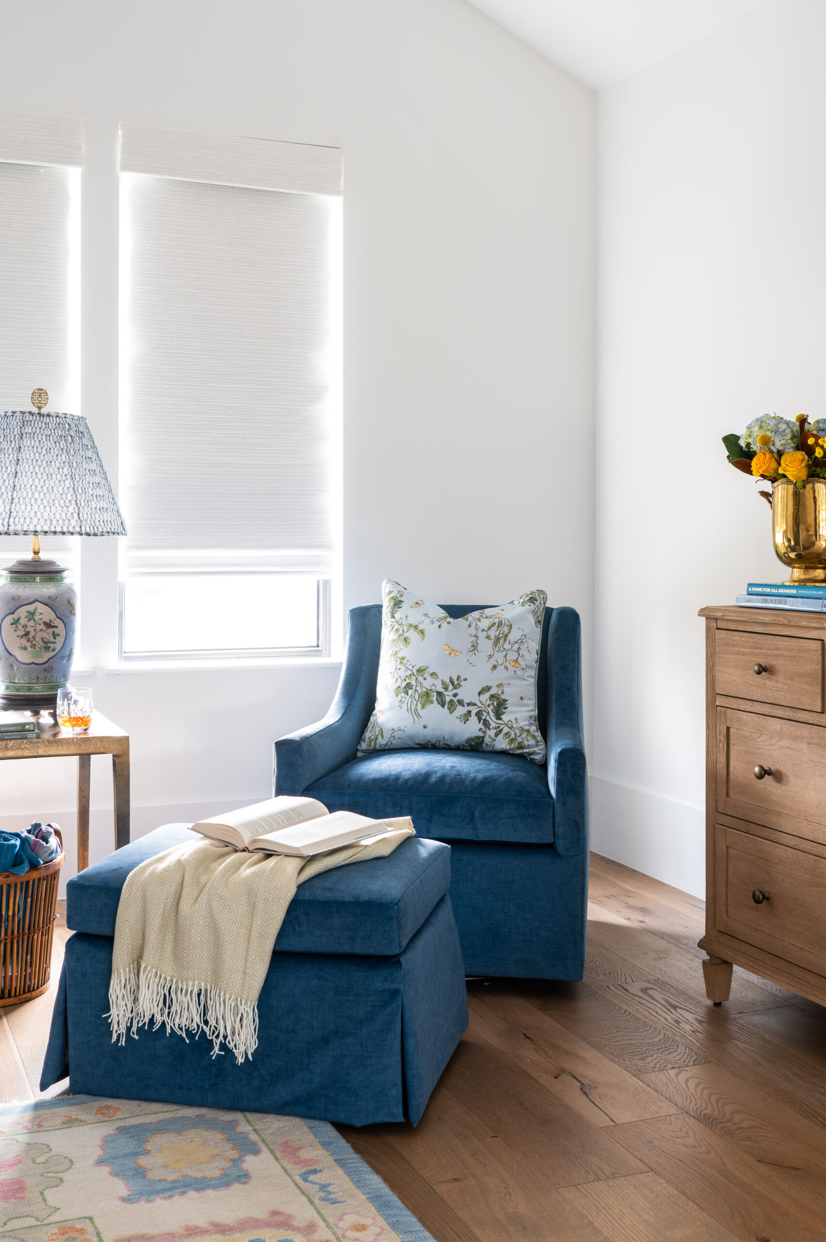 A comfortable corner with a blue accent chair and floral pillows.
