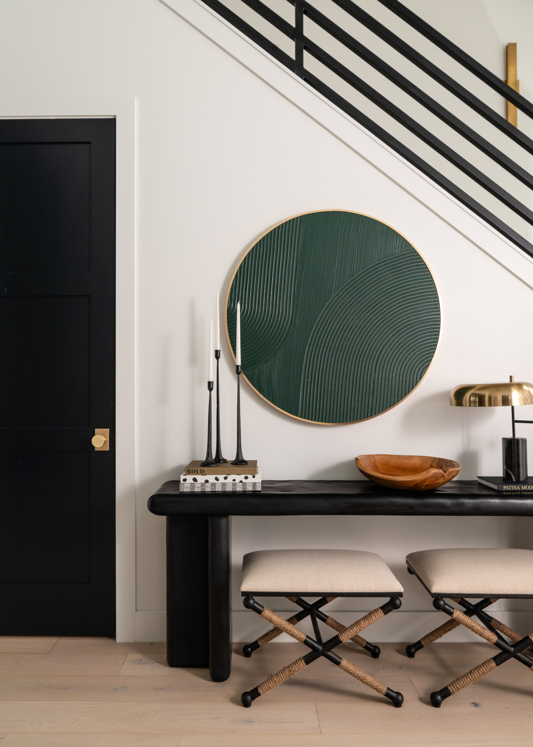 Modern home interior design featuring a contemporary entryway with a green abstract wall art piece, black and gold décor, and a sleek console table with stylish accents.