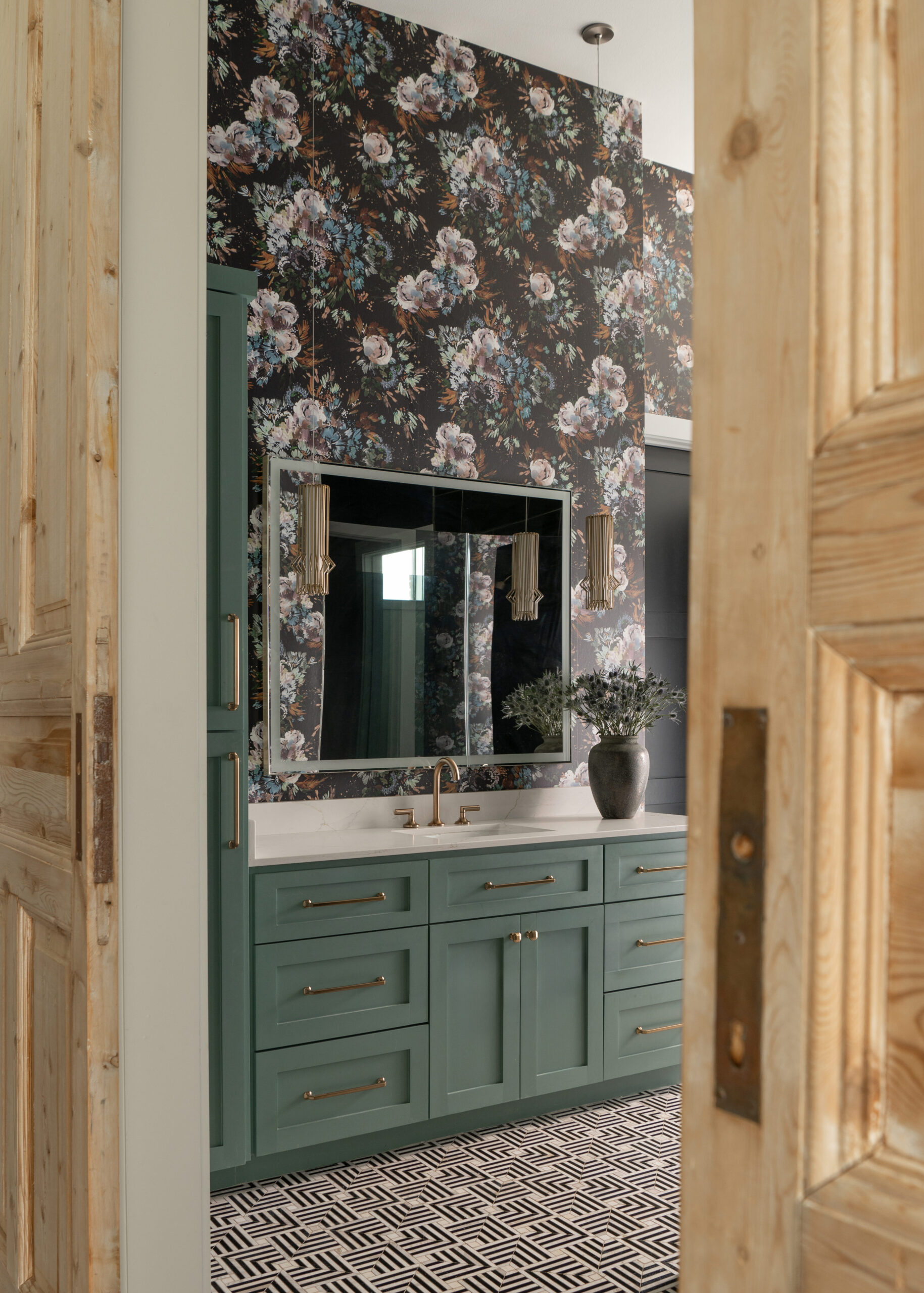 Modern home interior design featuring a green vanity in the bathroom with floral wallpaper and stylish finishes, giving the space an elevated, luxurious feel.