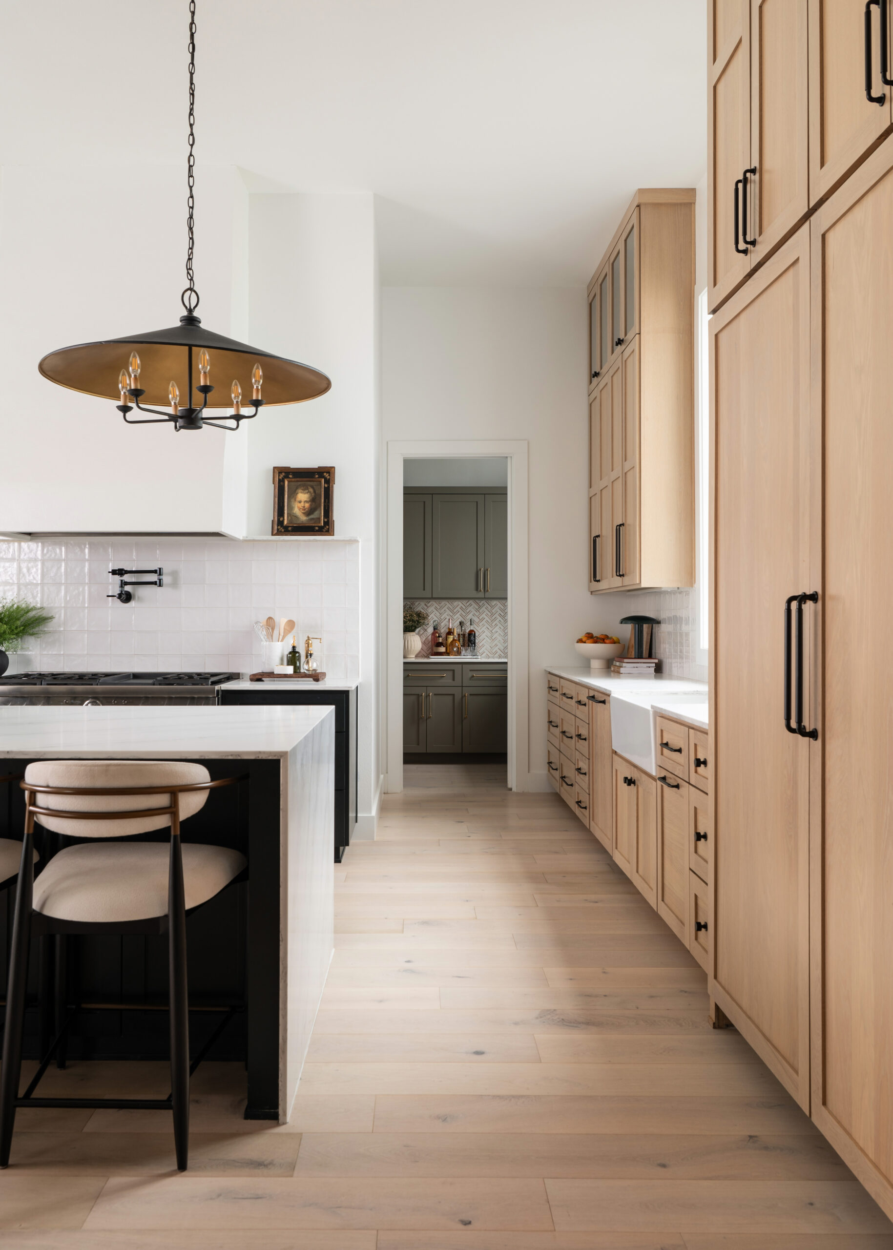 A modern kitchen featuring minimalist design with light wooden cabinetry, a large marble countertop, and elegant pendant lighting, capturing the essence of modern home interior design.